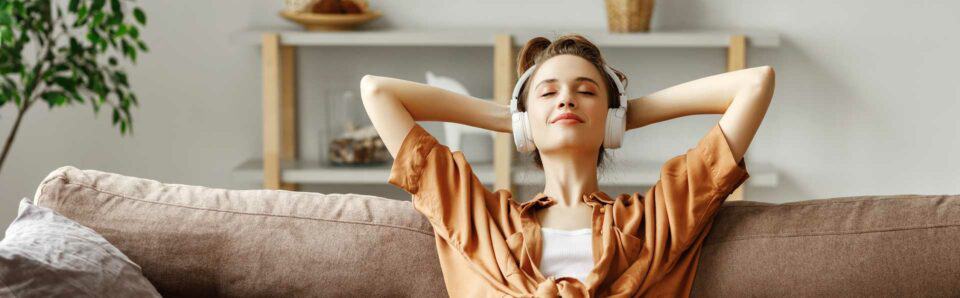 Nainen kuuntelemassa musiikkia kuulokkeilla maalämpöpumpun lämmittäessä asuntoa talvella