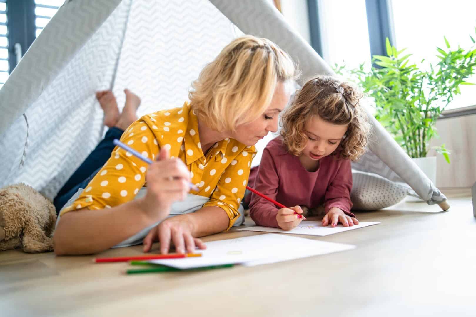 hero image - Lämpöpumput & LVI-työt | RH Kylmätekniikka Oy Äiti ja tyttö makoilemassa teltassa ja piirtämässä paperille